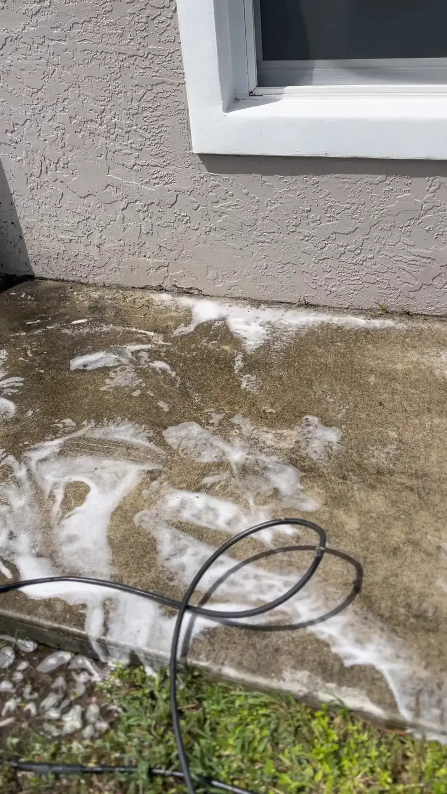 A concrete side walkway being pressure washed, with the dirt lifting away